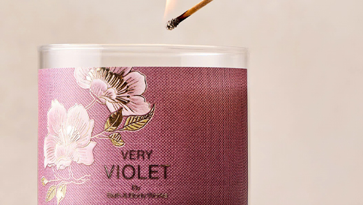 Hand lighting a Very Violet 3-Wick candle